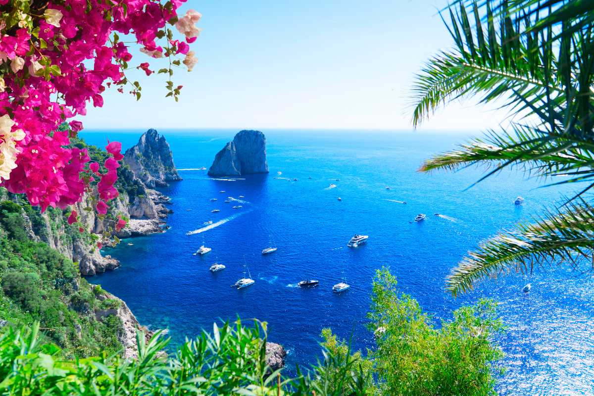 Vista panoramica dei Faraglioni al tramonto con barche in primo piano, atmosfera rilassante, Capri