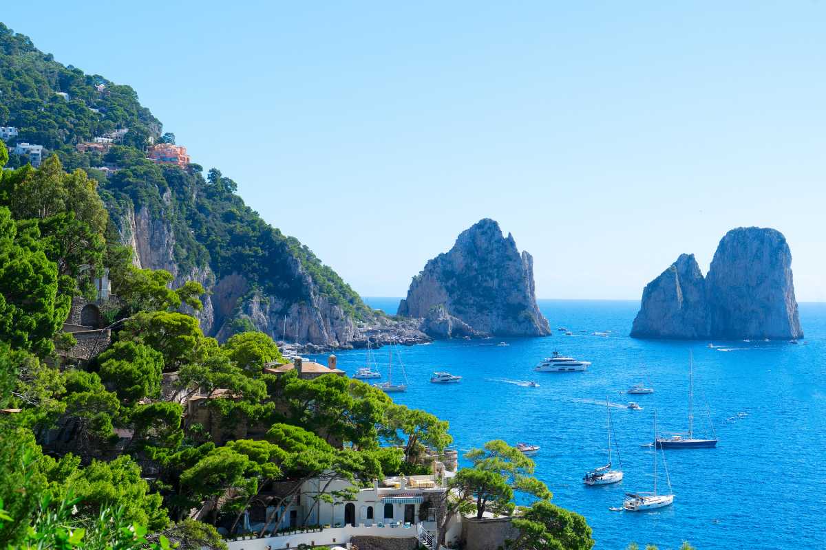 Scorcio di una sagra gastronomica estiva a Capri: tavolate con piatti tipici, totani fritti, limoni, vista sul mare, gente sorridente