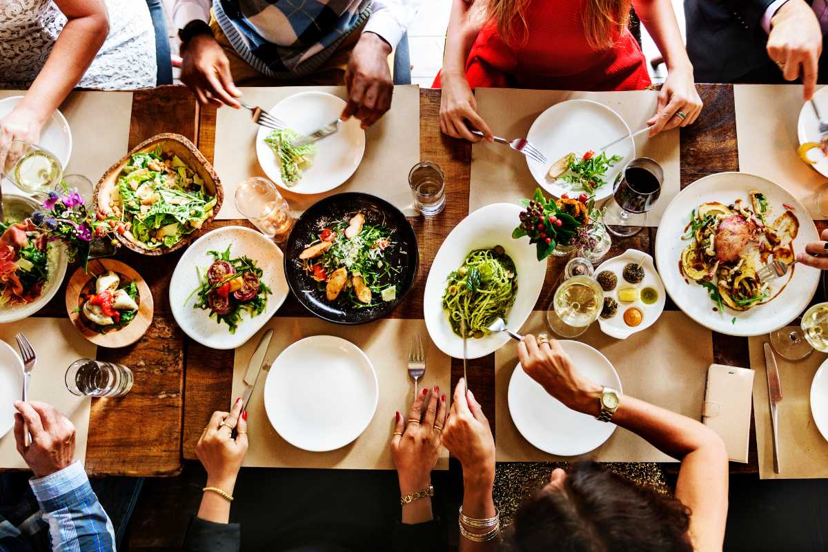 Dettaglio di una trattoria tipica a Capri centro: tavoli apparecchiati con piatti di ravioli capresi e torta caprese, arredi rustici e colori mediterranei, atmosfera accogliente